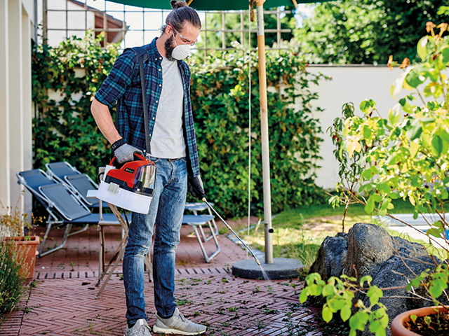 Düngen_Pflanzenschutz Mann mit Maske im Garten