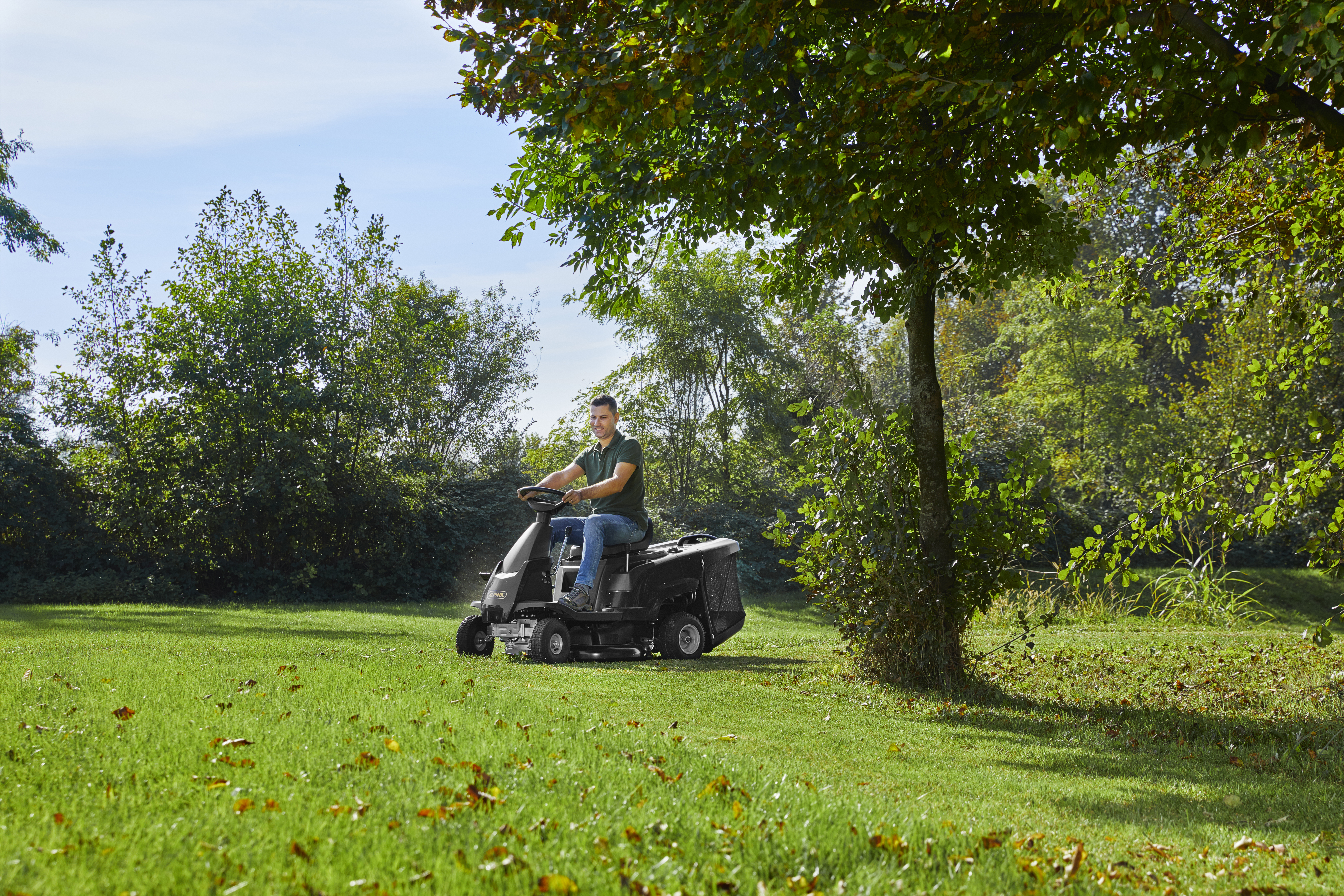 Ein Mann mäht den Rasen mit einem Rasentraktor.
