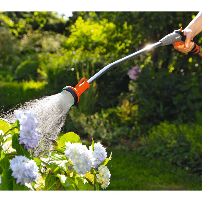 Ein Gießstab der Wasser auf Blumen spritzt