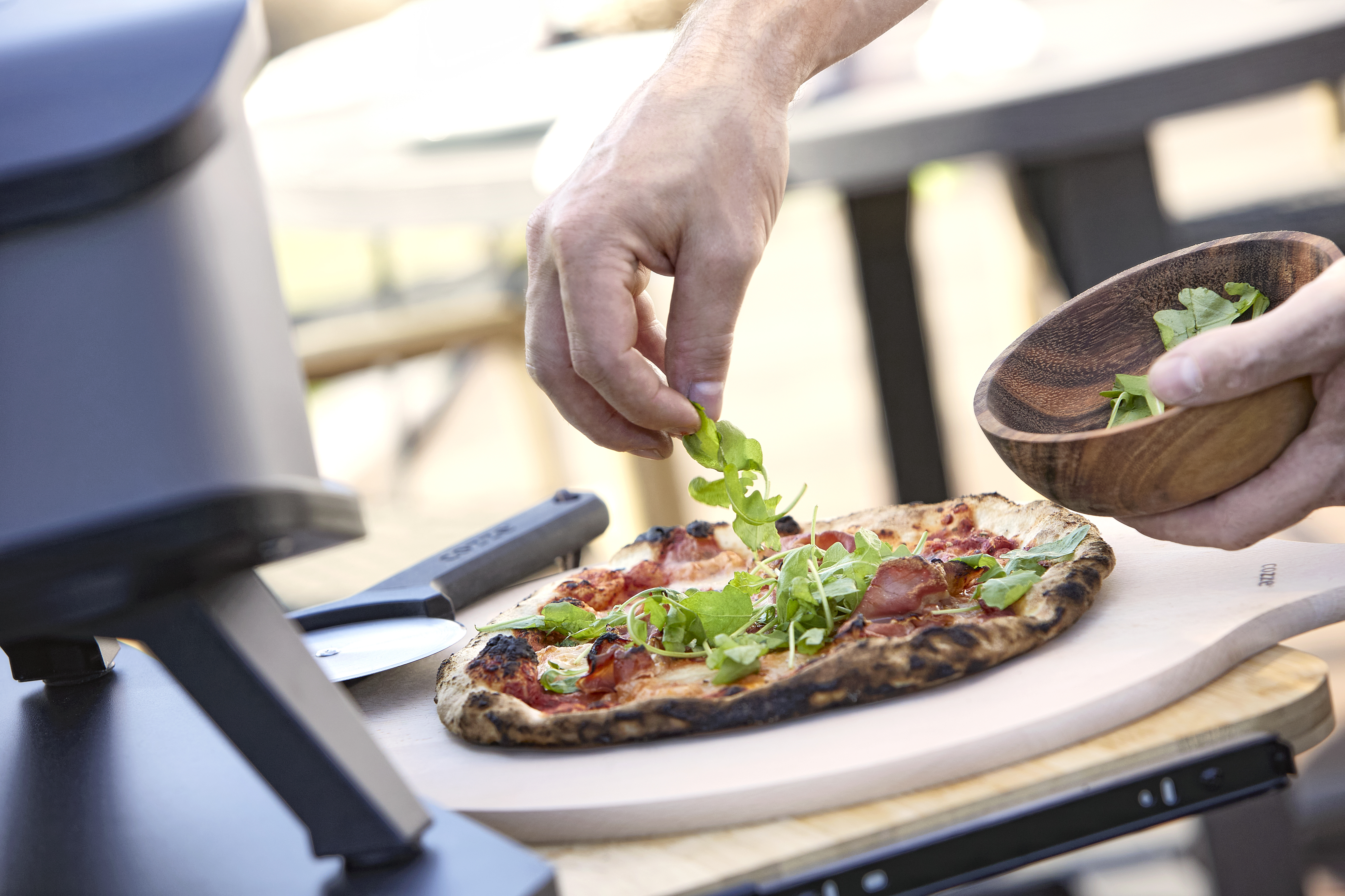 Pizza auf Pizzaschieber wird mit frischem Salat garniert