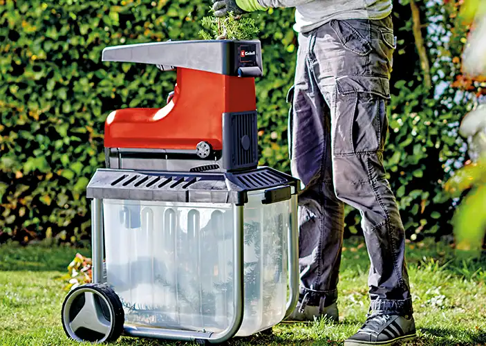 Häcksler wird im Garten von einer Person genutzt  Häcksler wird im Garten von einer Person genutzt