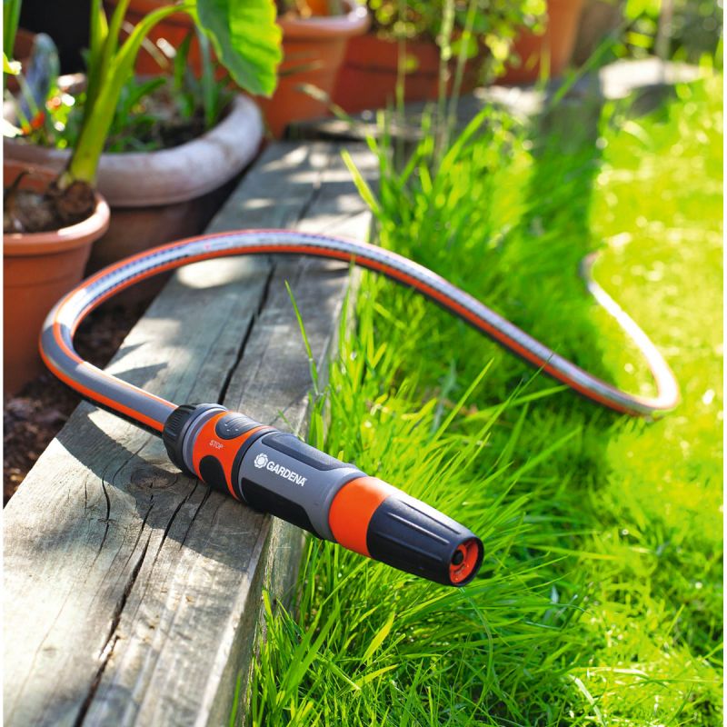 Eine Gardena Reinigungsbrause die an einem Blumenbeet liegt