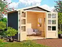 Ein Gartenschuppen mit offenen Türen zeigt innen ein Sofa, umgeben von Pflanzen im Garten.