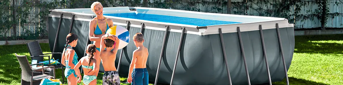 Eine Gruppe von Menschen spielt mit einem Ball neben einem Aufstellpool im Garten.