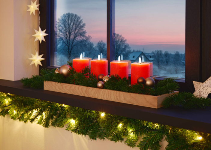 Adventskranz mit roten Kerzen auf einer geschmückten Fensterbank Adventskranz mit roten Kerzen auf einer geschmückten Fensterbank