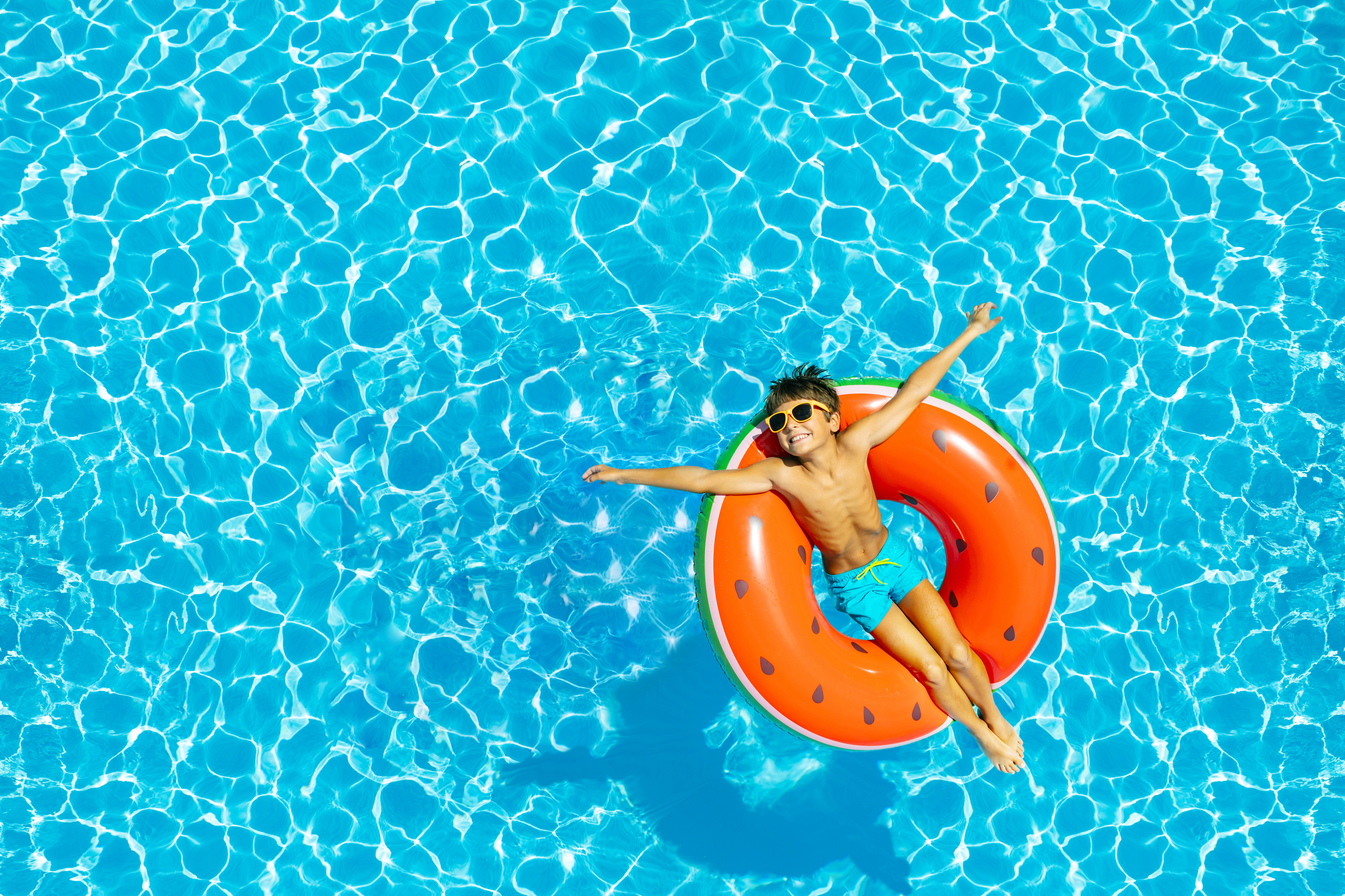 Ein Junge der auf einem Schwimmring im Pool liegt