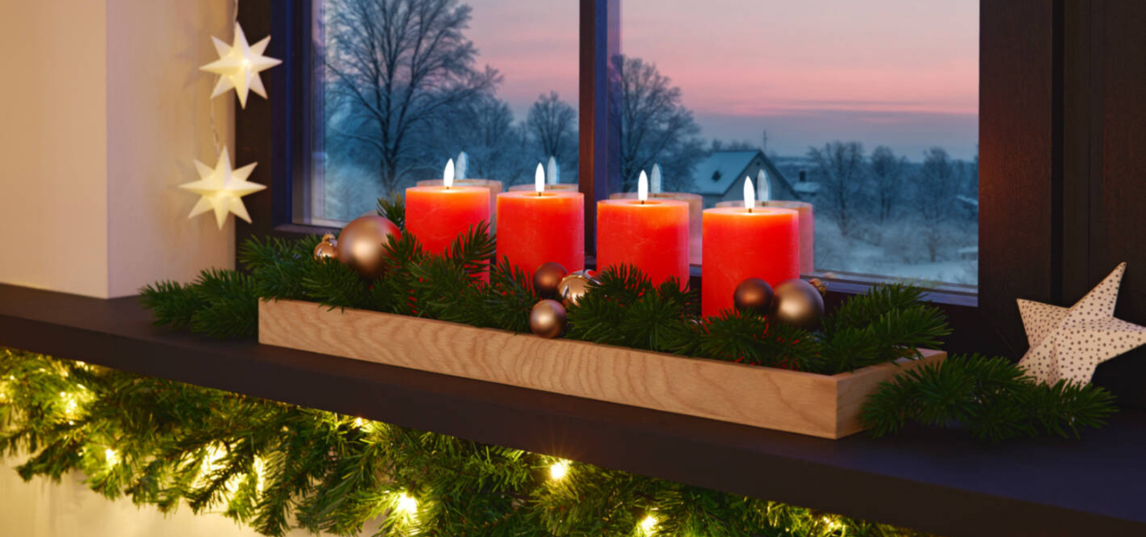 Adventskranz mit roten Kerzen auf einer geschmückten Fensterbank Adventskranz mit roten Kerzen auf einer geschmückten Fensterbank