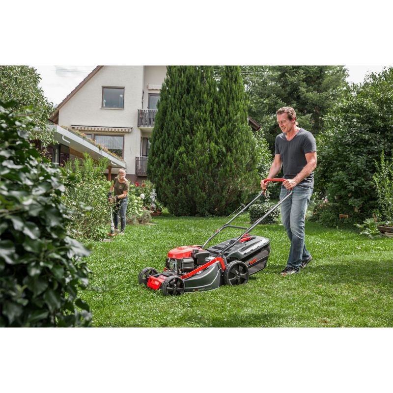 Benzinrasenmäher  der von einem Mann bedient wird